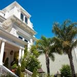 Elegant white Victorian-style mansion, with palm trees, on a sunny day in San Francisco.