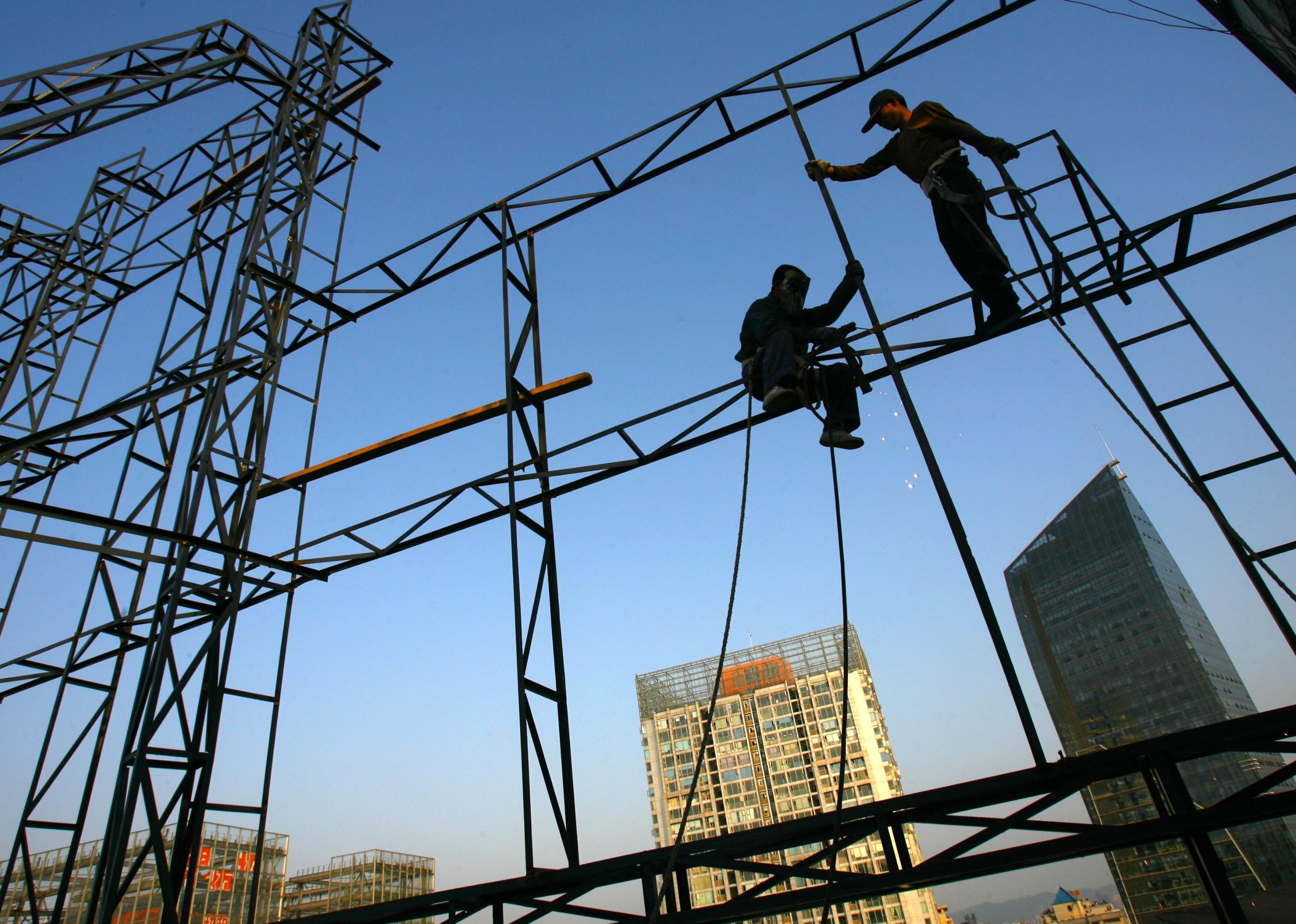 Workers weld on the roof of a building
