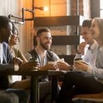 Group of friends having fun and laughing drinking coffee in coffeehouse.
