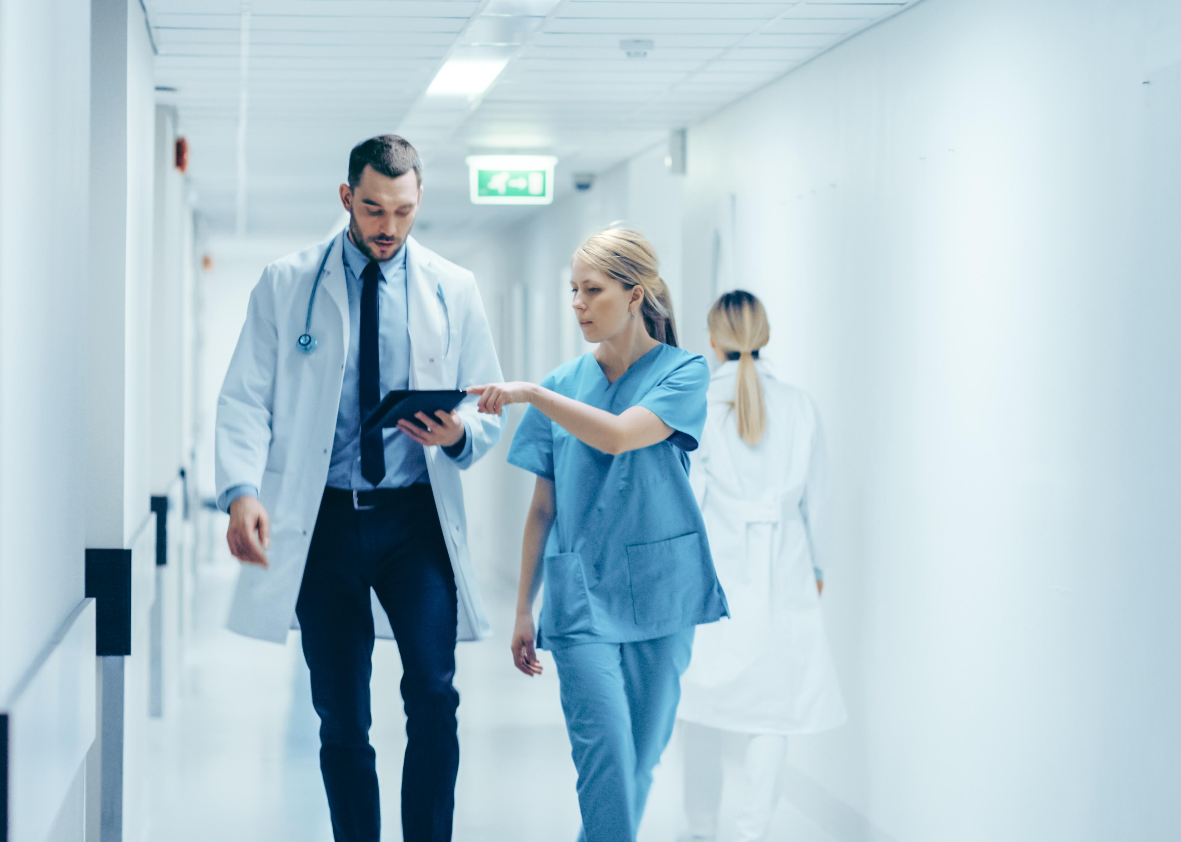 A doctor and nurse walk through a hospital.
