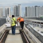 Workers moving equipment on a railway.