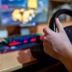 Teenager playing on truck driving simulator in front of a computer.