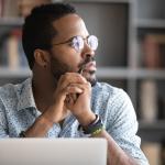 Man in glasses distracted from computer work.