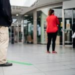 People standing in line in front of a store with distance between them per pandemic-related safety measures.