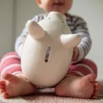 Young baby playing with a piggy bank.