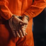 Handcuffs on an inmate in an orange jail jumpsuit.