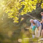 Boy, father, and grandfather fishing in lake.