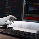 Robotic hand writing code on computer.