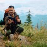Young man on a smartphone while hiking in the mountains.
