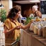 Woman in a zero waste store looking at jars of dried goods.