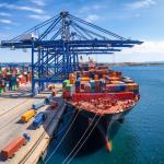 A large container cargo ship is being unloaded in a commercial dock.