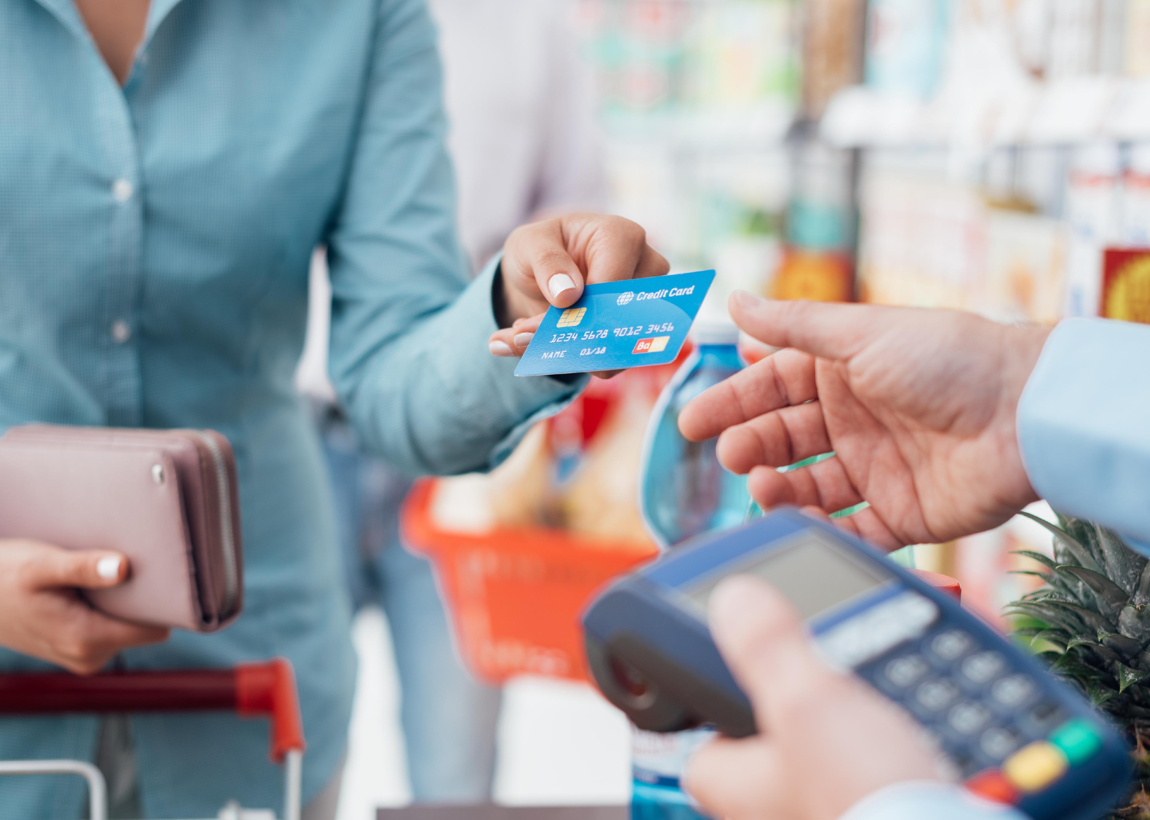 Woman at a supermarket checkout paying using a credit card