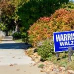 Harris-Walz yard lawn sign in a residential garden near a sidewalk in California.