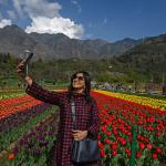 A woman taking a selfie in a field of flowers.