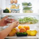 Hands opening fridge door and putting package of food in it.