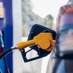 A dark-colored sedan being filled up at a gas station.