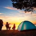 Family of four set up camp near the lake and watching the sunset.