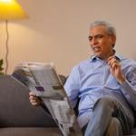 Senior man reading a newspaper in confusion.