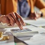 Tax professional using a calculator while reviewing finance documents.