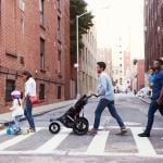 Two families crossing a road along an apartment neighborhood.