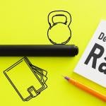 Icons representing money and debt on opposite sides of a line, balancing on a wallet symbolizing income on a flourescent yellow background, with a white post it saying "Debt to Income Ratio."