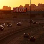 A billboard shows the current temperature over 100 degrees on June 05, 2024 in Phoenix, Arizona as drivers travel on the freeway in the foreground in the shadow of the setting sun.