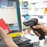 Pharmacist scanning price on a box of medicine.
