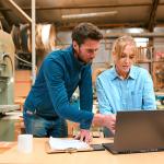 A pair of woodwork business owners reviewing reports in a laptop.