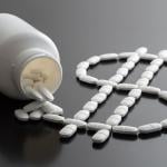Pills from a bottle forming a dollar sign as a concept of rising medicine costs.