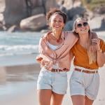 A happy lesbian couple walking on the beach.
