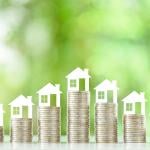 Tiny figures of residential houses atop coin stacks.
