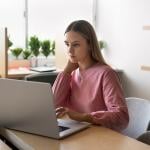 Young college student using a laptop to browse through finances.