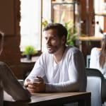 Millenial couple sitting at a cafe table engaged in discussion.