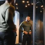 A stylish man looking in front of the mirror to check his outfit.