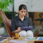 Young businesswoman in workplace using a tablet to browse information online.