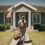 Female veteran soldier with luggages coming home and standing in front of her house.