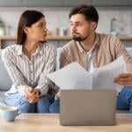 Young couple looking at each other with a serious expression while going through financial documents.