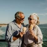 An older couple eating ice cream while standing on the Santa Monica pier.