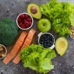 A selection of healthy foods such as salmon fish, superfoods, nuts, fruits, berries and leafy vegetables.