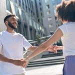 Young Black couple facing each other holding hands and playing around, dancing.