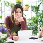 A flower shop owner carefully reviewing business documents while at the store.