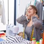 A tailoring shop owner holding the back of her neck from being tired and stressed.