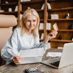 Senior businesswoman using company card to pay a bill online.