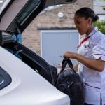 A travel nurse putting her bag in the trunk of her car.