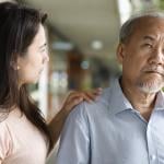 A middle-aged daughter looking worried at his elderly father who has dementia.