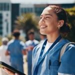 A nursing student happily using a tablet inside campus.
