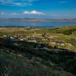 A view of Bear Lake with mountains in the distance with hills and homes in the foreground from July 2024.