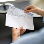 Worker pulling out a paycheck from its envelope.