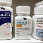 Bottles of ADHD medications such as Adderall, Concerta, and Ritalin.