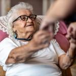 An elderly woman being assisted by her caregiver to stand up.